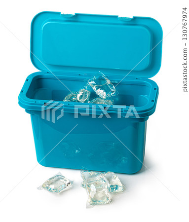Laundry detergent pods spilling from blue container on white background 130767974