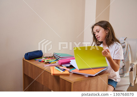 Young Girl Studying with Notebooks on Desk in Home Study Area 130768070