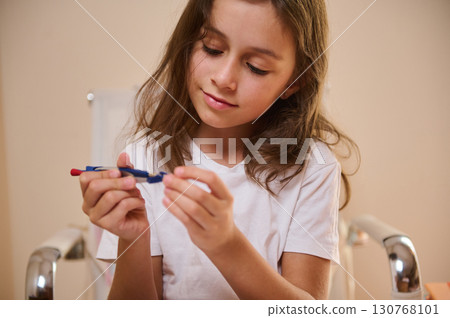 Young Girl Seated Calmly Holding a Blue and Red Drawing Tool Young Girl Seated Calmly Holding a Blue and Red Drawing Tool 130768101