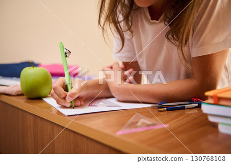 Student Working on Homework at Desk with Supplies and a Healthy Snack 130768108