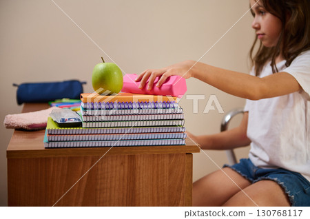 Young Student Organizing School Supplies at Desk for Productive Study Session 130768117