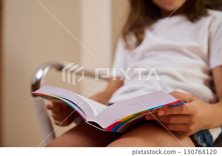 A Child Relaxing with a Book at Home on a Comfortable Chair A Child Relaxing with a Book at Home on a Comfortable Chair 130768120