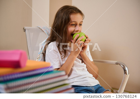 Young Student Enjoying a Tasty Green Apple During a Study Break Young Student Enjoying a Tasty Green Apple During a Study Break 130768124