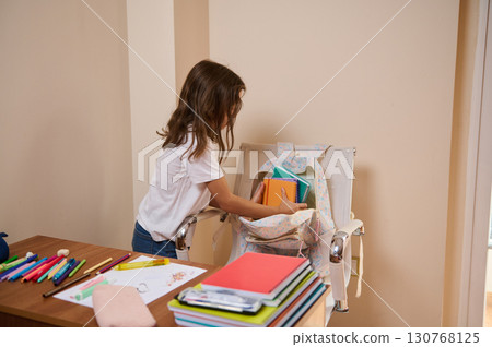 Girl Organizing School Supplies with Backpack at Home Study Area Girl Organizing School Supplies with Backpack at Home Study Area 130768125