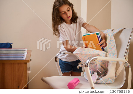 Young Girl Organizing School Supplies Into a Backpack in a Study Room Young Girl Organizing School Supplies Into a Backpack in a Study Room 130768126