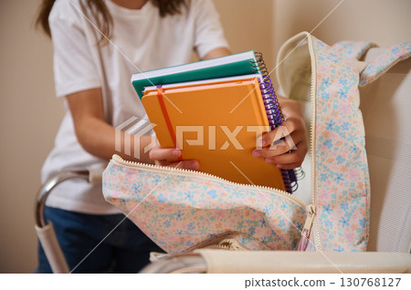 Student Organizing Books and Supplies into Floral Backpack at Home 130768127