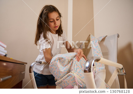 Young Girl Organizing a Backpack at Home in a Casual Setting 130768128