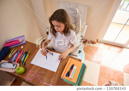 Young Girl Drawing with Compass at Desk in Brightly Lit Room Young Girl Drawing with Compass at Desk in Brightly Lit Room 130768143