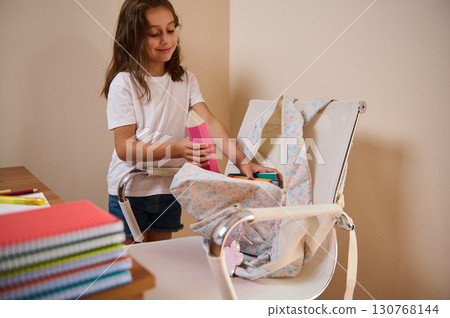 Young Girl Organizing School Supplies Into Her Backpack at Home Young Girl Organizing School Supplies Into Her Backpack at Home 130768144