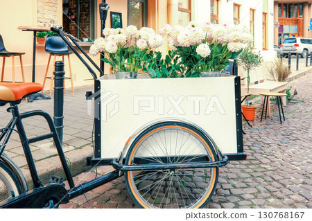 Cargo bike tricycle with white chrysanthemums bouquet parked near flower shop 130768167