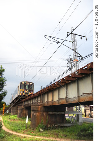Iwami Kagura wrapping train (Kiha 126 series diesel railcar) passing over a low-profile iron bridge in the city 130768309