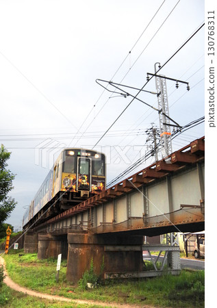 Iwami Kagura wrapping train (Kiha 126 series diesel railcar) passing over a low-profile iron bridge in the city Iwami Kagura wrapping train (Kiha 126 series diesel railcar) passing over a low-profile iron bridge in the city 130768311