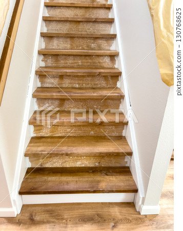 A straight-on view of a staircase shows laminate flooring nearly finished, with some protective materials still visible. Lighting is bright and consistent across the scene. 130768625