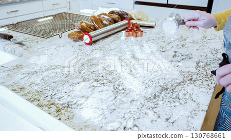 Using an adjustable rolling pin to roll out gingerbread cookie dough on the elegant marble counter in a modern kitchen, getting ready for festive holiday baking. 130768661