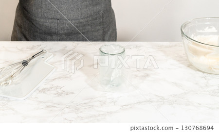 A clean glass filled with freshly prepared Simple White Royal Icing next to a mixing bowl and whisk, ready for decorating baked goods. A clean glass filled with freshly prepared Simple White Royal Icing next to a mixing bowl and whisk, ready for decorating baked goods. 130768694