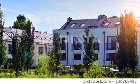 Harmony with nature, eco architecture. Terraced single family homes in newly developed housing estate. The real estate market in the suburbs with lush greenery surrounding. Harmony with nature, eco architecture. Terraced single family homes in newly developed housing estate. The real estate market in the suburbs with lush greenery surrounding. 130769485