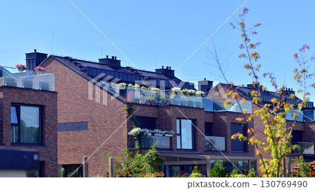 Harmony with nature, eco architecture. Terraced single family homes in newly developed housing estate. The real estate market in the suburbs with lush greenery surrounding. Harmony with nature, eco architecture. Terraced single family homes in newly developed housing estate. The real estate market in the suburbs with lush greenery surrounding. 130769490