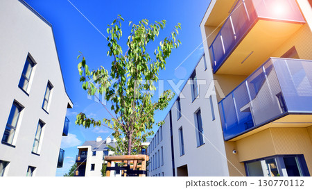 European residential architecture harmonizing with nature. Eco-friendly living in city with greens. Eco apartment building saving energy and fresh air concept.  130770112