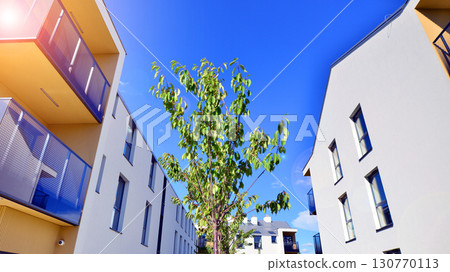 European residential architecture harmonizing with nature. Eco-friendly living in city with greens. Eco apartment building saving energy and fresh air concept. European residential architecture harmonizing with nature. Eco-friendly living in city with greens. Eco apartment building saving energy and fresh air concept. 130770113
