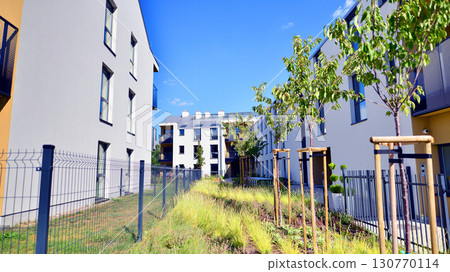 European residential architecture harmonizing with nature. Eco-friendly living in city with greens. Eco apartment building saving energy and fresh air concept. European residential architecture harmonizing with nature. Eco-friendly living in city with greens. Eco apartment building saving energy and fresh air concept. 130770114