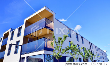 European residential architecture harmonizing with nature. Eco-friendly living in city with greens. Eco apartment building saving energy and fresh air concept. European residential architecture harmonizing with nature. Eco-friendly living in city with greens. Eco apartment building saving energy and fresh air concept. 130770117