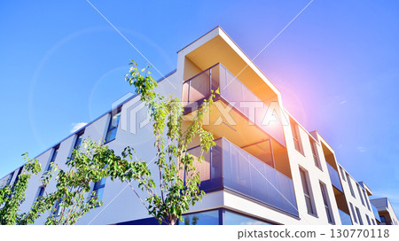 European residential architecture harmonizing with nature. Eco-friendly living in city with greens. Eco apartment building saving energy and fresh air concept.  130770118