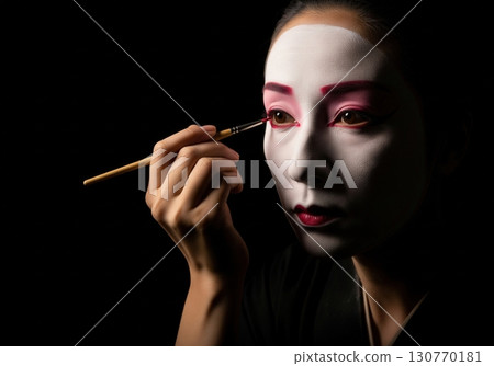 Japanese woman in a kimono applying traditional kabuki or geisha makeup with a brush 130770181