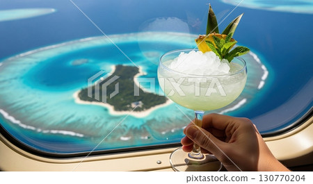 Hand holding a missionary's downfall cocktail on a plane with a tropical island view 130770204