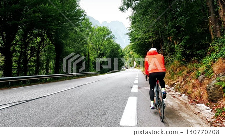 Cyclist riding on a mountain road in forest with following camera view, French Alps Cyclist riding on a mountain road in forest with following camera view, French Alps 130770208