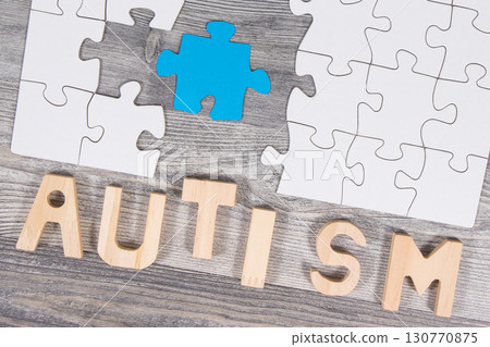 White and blue puzzle. Inscription autism. Symbol of Autism Spectrum Disorder. Autism Awareness Day White and blue puzzle. Inscription autism. Symbol of Autism Spectrum Disorder. Autism Awareness Day 130770875