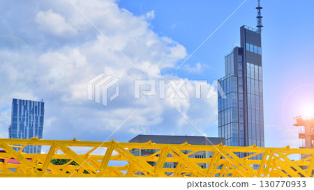 Modern office building with glass facade. Transparent glass wall of office building. Reflection of the blue sky on the facade of the building. Modern office building with glass facade. Transparent glass wall of office building. Reflection of the blue sky on the facade of the building. 130770933