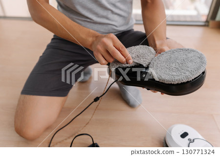 Homeowner preparing robotic window cleaner by changing mop and getting ready to clean windows, ensuring spotless shine and maintaining comfortable modern living space, close-up. 130771324