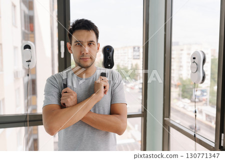Portrait of confident window washer controlling robotic cleaning devices during high-rise exterior maintenance, showcasing advanced technological efficiency in urban environment, looking at camera 130771347