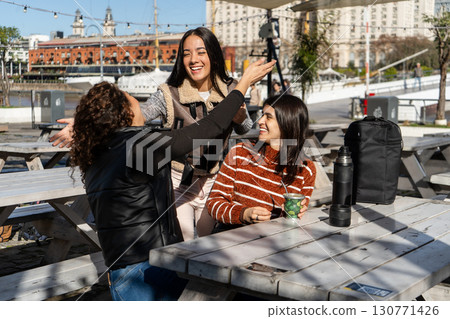 Three happy latin friends greeting each other in puerto madero, buenos aires 130771426