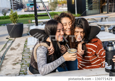 Latin american women sharing mate outdoors and embracing friendship Latin american women sharing mate outdoors and embracing friendship 130771429