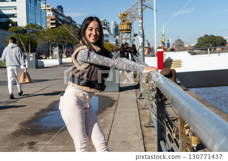 Young woman leaning on a bridge railing enjoying the view of puerto madero 130771437
