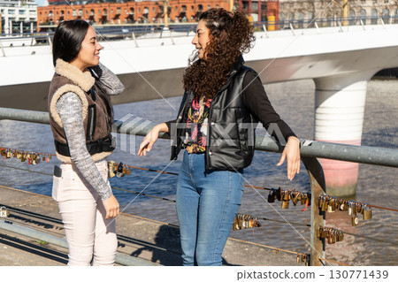 Two young women talking on bridge with love locks in buenos aires 130771439