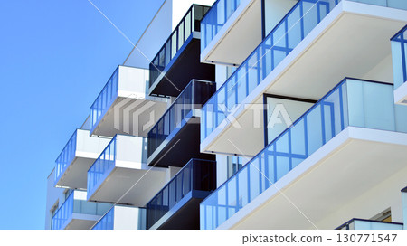 Modern apartment buildings on a sunny day with a blue sky. Facade of a modern apartment building. Modern residential apartment building complex condo. Modern apartment buildings on a sunny day with a blue sky. Facade of a modern apartment building. Modern residential apartment building complex condo. 130771547