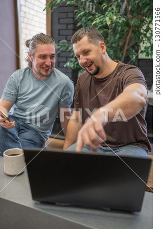 Two men actively collaborating together on a laptop in a modern and stylish office space Two men actively collaborating together on a laptop in a modern and stylish office space 130771566