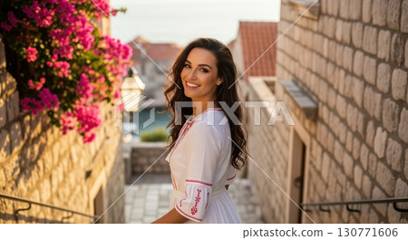Beautiful smiling woman in a white dress in an old mediterranean town during a golden sunset 130771606