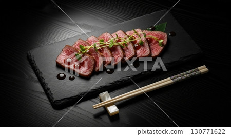 Japanese wagyu beef tataki sliced and served with a savory sauce on a black slate platter Japanese wagyu beef tataki sliced and served with a savory sauce on a black slate platter 130771622