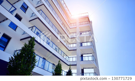Modern apartment building with balconies and greenery. Beautiful view of real estate buildings in summer. Walking area with trees and grass. Modern residential buildings in the public green area. Modern apartment building with balconies and greenery. Beautiful view of real estate buildings in summer. Walking area with trees and grass. Modern residential buildings in the public green area. 130771729
