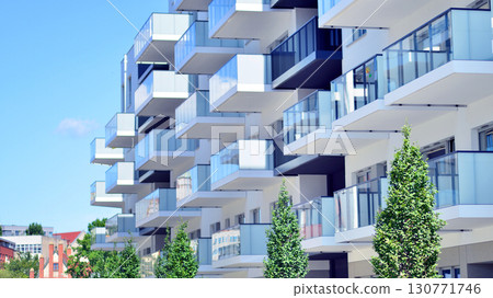 Modern apartment building with balconies and greenery. Beautiful view of real estate buildings in summer. Walking area with trees and grass. Modern residential buildings in the public green area. Modern apartment building with balconies and greenery. Beautiful view of real estate buildings in summer. Walking area with trees and grass. Modern residential buildings in the public green area. 130771746