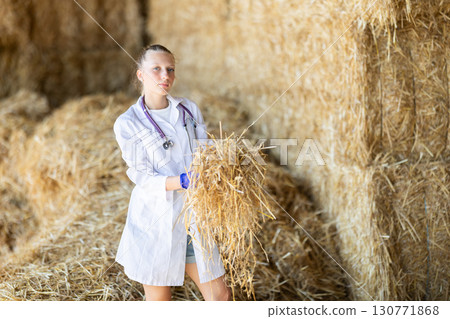 Young woman veterinarian checking straw for cows Young woman veterinarian checking straw for cows 130771868