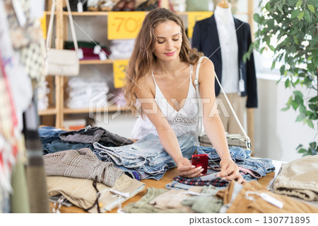 Happy young woman scanning QR-code on pantaloons in clothing store 130771895