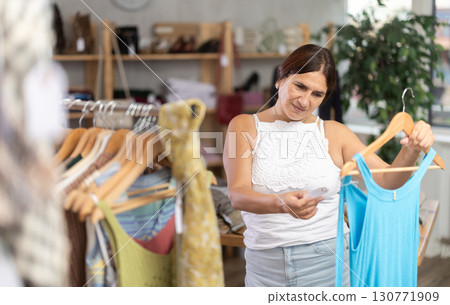 Latin woman customer turn over and choose something summer cloth in store, 130771909