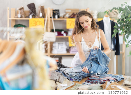 Young woman choosing jean shorts in clothing store Young woman choosing jean shorts in clothing store 130771912