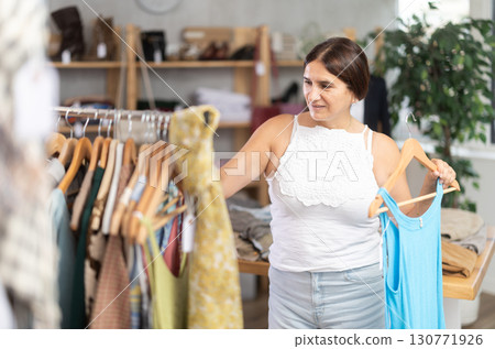 Latin woman customer turn over and choose something summer cloth in store, Latin woman customer turn over and choose something summer cloth in store, 130771926