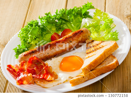 Fried egg, sausage, bacon and grilled bread 130772158