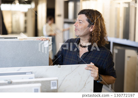 Confident male customer picking out wall tile materials for bathroom in hardware store 130772197